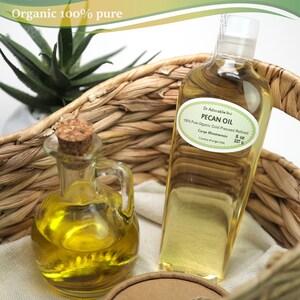 May include: Two glass bottles of organic pecan oil, one large and one small, in a woven basket. The larger bottle is labeled "Dr Adorable Inc Pecan Oil 100% Pure Organic Cold Pressed Refined Carya illinoinensis 8 oz 227 g Country of origin USA".