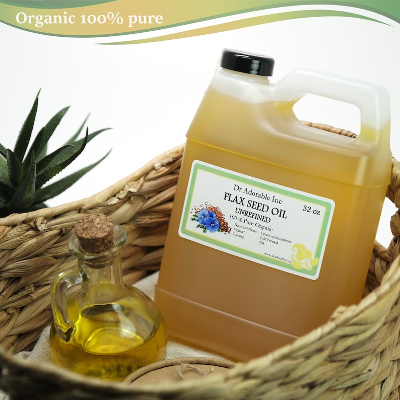 May include: A large, clear plastic jug of flax seed oil with a black cap and white handle. A smaller glass bottle of oil sits in front. The label reads "Flax Seed Oil Unrefined 100% Pure Organic" and "32 oz".