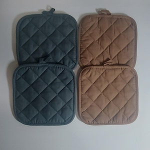 May include: Four square quilted pot holders in teal and tan. Each has a diamond pattern and a loop for hanging. The pot holders are made of a soft, padded material. They are suitable for use in the kitchen.