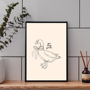 Minimalist line drawing of a goose wearing a bow, with playful handwritten text saying “you silly goose,” set on a soft cream background.