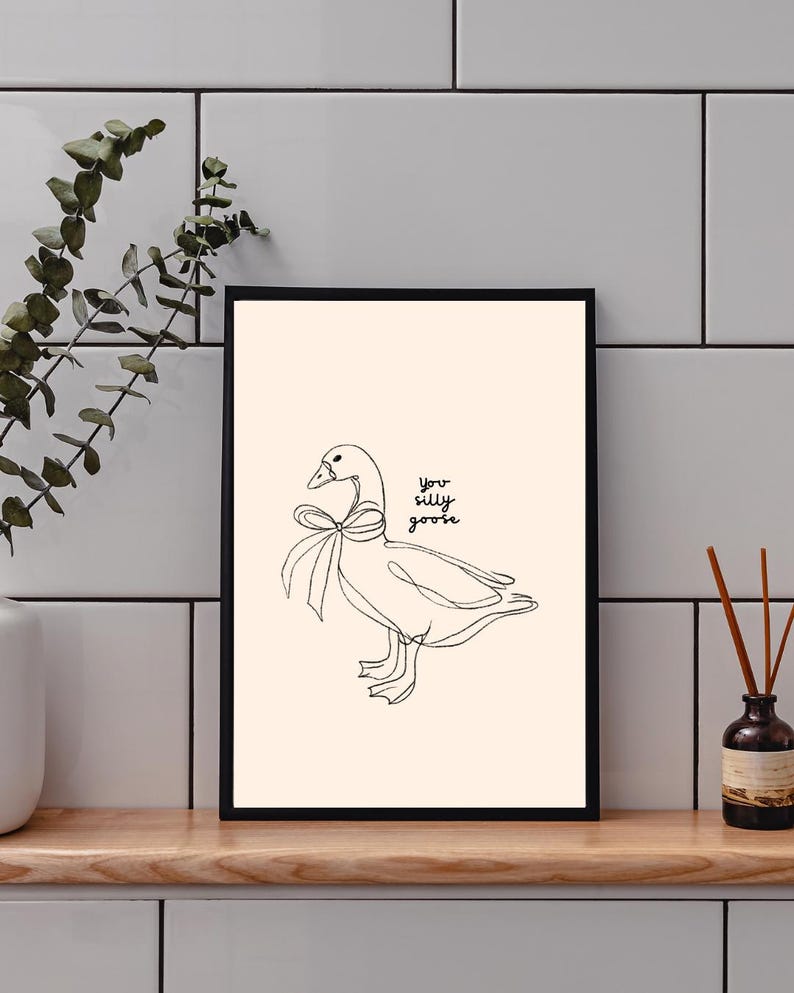Minimalist line drawing of a goose wearing a bow, with playful handwritten text saying “you silly goose,” set on a soft cream background.