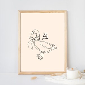 Minimalist line drawing of a goose wearing a bow, with playful handwritten text saying “you silly goose,” set on a soft cream background.