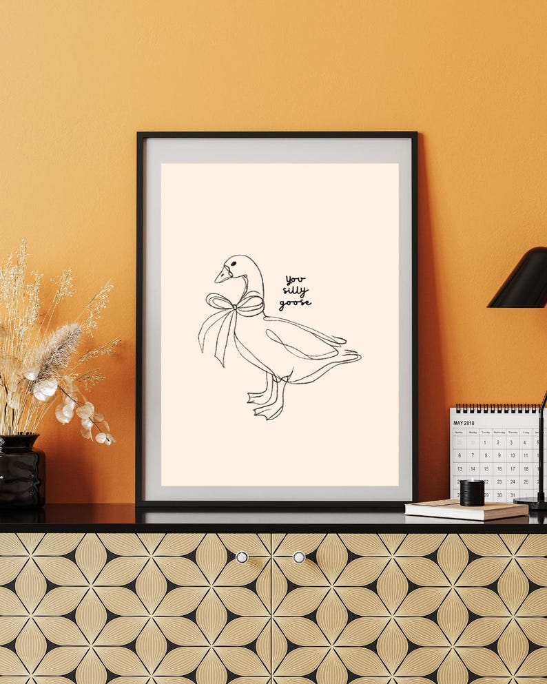 Minimalist line drawing of a goose wearing a bow, with playful handwritten text saying “you silly goose,” set on a soft cream background.