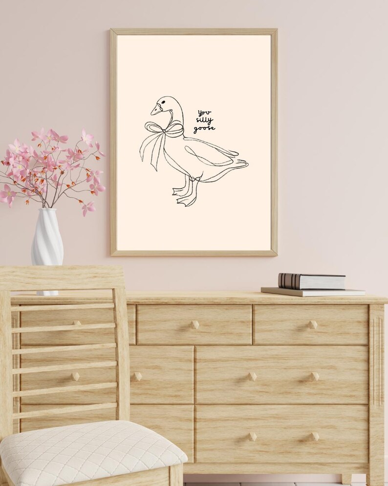 Minimalist line drawing of a goose wearing a bow, with playful handwritten text saying “you silly goose,” set on a soft cream background.