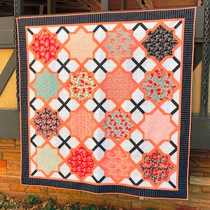 May include: A quilt with a black and white geometric pattern and a variety of floral patterns in shades of pink, red, and green.