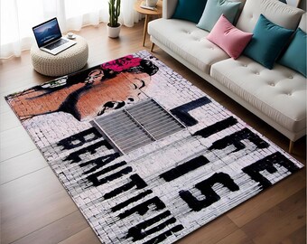 Puede incluir: Una alfombra blanca y negra con un patrón de ladrillo y las palabras "Life is Beautiful" en pintura negra. El rostro de una mujer es parcialmente visible en la esquina superior izquierda de la alfombra.