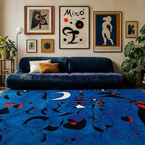 May include: A rectangular area rug featuring a vibrant blue background with abstract black line art, red geometric shapes, and a white crescent moon. The design includes various circular and angular motifs scattered across the surface.
