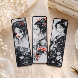 Könnte beinhalten: Drei rechteckige Lesezeichen mit Illustrationen von Frauen in traditioneller japanischer Kleidung. Die Lesezeichen haben schwarze Ränder und zeigen Frauen mit Blumenschmuck im Haar und detaillierter Kleidung. Bücher und eine Teetasse sind im Hintergrund.