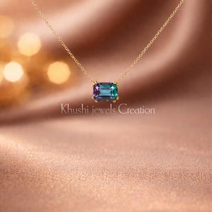 Peut inclure: Un collier en or avec un pendentif rectangulaire en pierre précieuse changeant de couleur. Le pendentif passe du violet au turquoise. Le collier est présenté sur un fond satiné. Le texte sur l'image indique "Khushi jewels Creation."
