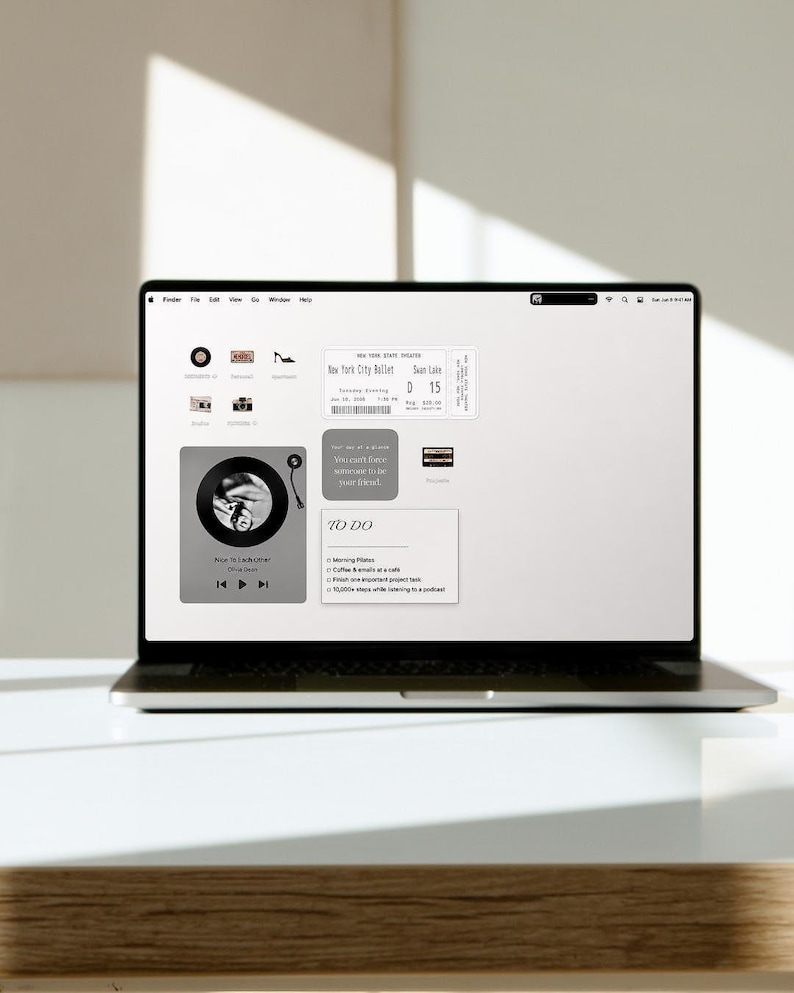 May include: A laptop screen displaying a digital desktop interface with various icons and widgets, including a New York City Ballet ticket, a music player widget showing Nice To Each Other by Olivia Dean, and a To Do list with daily tasks.