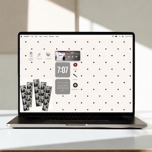 May include: A laptop screen displaying a desktop interface with a white background featuring a black polka dot pattern. The screen shows various widgets, including a music player, a digital clock reading 7:07, and photo strips of people.