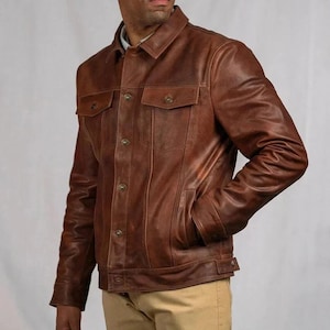 Può includere: Giacca in pelle marrone con chiusura a bottoni, due tasche sul petto e due tasche laterali. La giacca ha un colletto classico e polsini con bottoni. La pelle ha un aspetto invecchiato, che le conferisce un aspetto vintage.