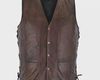 May include: A brown leather vest with a V-neck, button closure, and two front pockets. The vest has side laces and a dark interior. The leather has a distressed appearance.