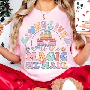 Op de afbeelding: Roze T-shirt met een regenboogkasteel-afbeelding en de tekst "Long Live All the Magic We Made".