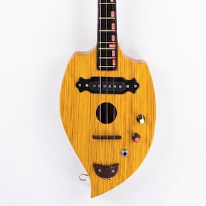 May include: A wooden stringed instrument with a carved bird head design. The instrument has a light brown body with a black fretboard and red fret markers. The instrument has a unique shape and design.