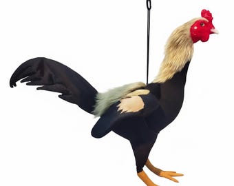 May include: A plush rooster toy with a black body, tail, and wings. It has a tan neck and a red comb and wattle. The rooster is suspended by a black string.