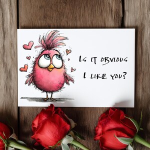 May include: A greeting card with a cartoon pink bird and the text "Is it obvious I like you?" is displayed on a wooden surface. Red roses are at the bottom of the image. The bird has large blue eyes and is surrounded by small red hearts.