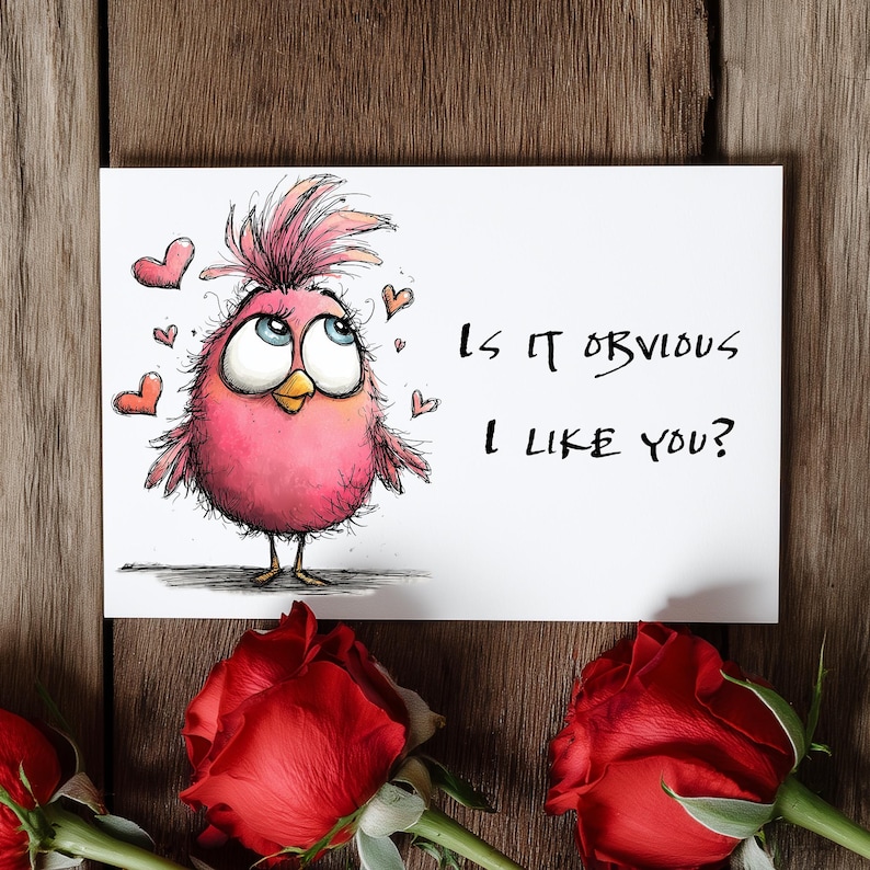 May include: A greeting card with a cartoon pink bird and the text "Is it obvious I like you?" is displayed on a wooden surface. Red roses are at the bottom of the image. The bird has large blue eyes and is surrounded by small red hearts.