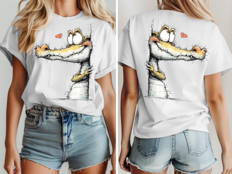 May include: White t-shirt featuring a whimsical illustration of a smiling alligator with a heart. The alligator has yellow and orange accents. The design is on the front and back of the shirt. The shirt is a casual, everyday wear item.