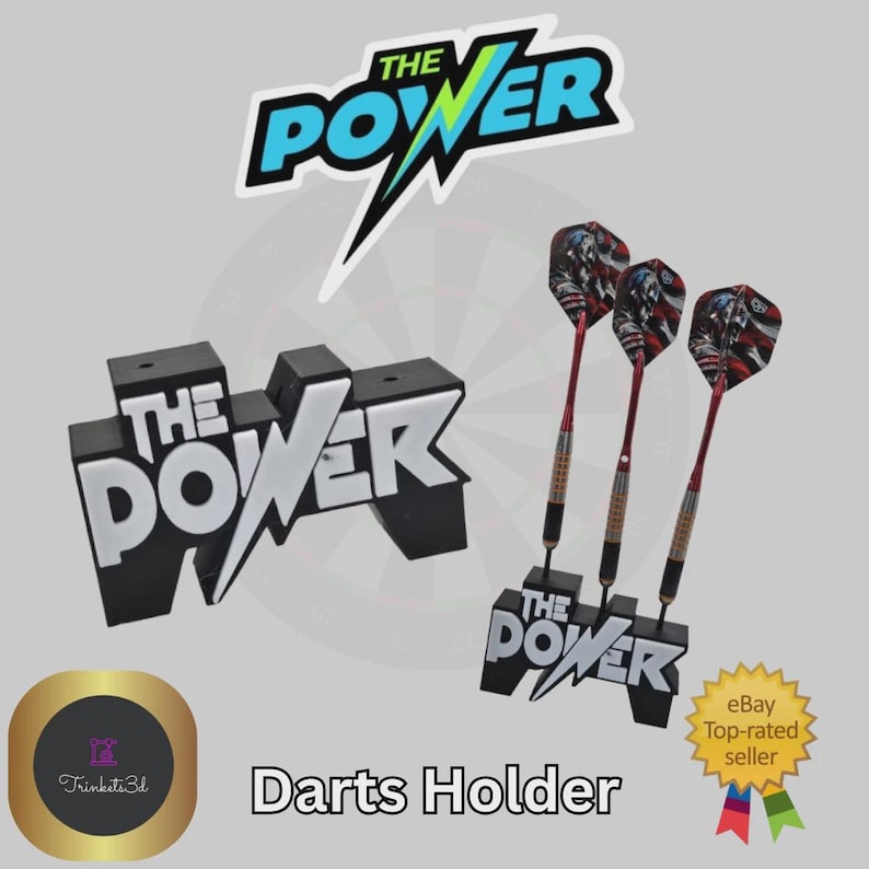 May include: Black and white "THE POWER" darts holder with three darts. The holder has a black base with white lettering. The darts have red shafts and patterned flights. The image also includes a "THE POWER" logo and the text "Darts Holder".