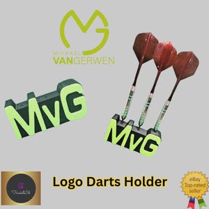May include: A black and green logo darts holder with the letters "MVG" in a neon green color. Three darts with red flights are in the holder. The text "Logo Darts Holder" is below the holder.