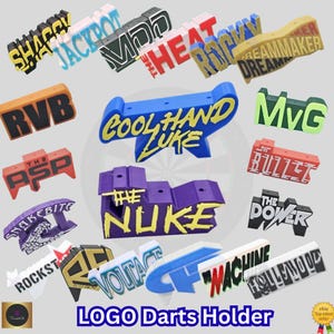 May include: A collection of colorful logo dart holders in various designs. The holders feature text such as "SHAGGY", "JACKPOT", "COOL HAND LUKE", and "THE NUKE". The text is in bold, contrasting colors. The image also includes the text "LOGO Darts Holder".