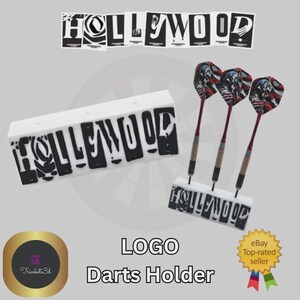 May include: White rectangular dart holder with the word "HOLLYWOOD" in black block letters. Three darts with red shafts and American flag-themed flights are displayed. The text "LOGO Darts Holder" is below.