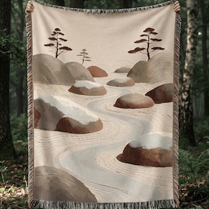 Peut inclure: Un plaid tissé présentant un motif de paysage avec des arbres stylisés, de gros rochers arrondis et un chemin sinueux dans des tons beige, marron et crème. La couverture rectangulaire possède des bords à franges en haut et en bas.