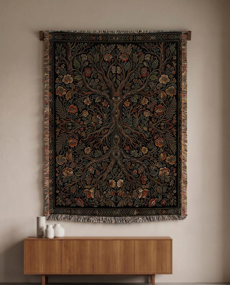 May include: A woven tapestry with a tree of life design, featuring intricate floral and foliage patterns in shades of brown, red, and green against a black background. The tapestry has a fringed edge and is mounted on a wooden rod.