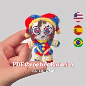 May include: A small, handmade crochet doll of a jester character with a white face, brown hair, and large eyes. The doll wears a red, blue, and yellow jester hat and matching outfit. The text reads PDF Crochet Pattern JESTER POMNI.