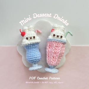 Puede incluir: Dos mini bebidas de postre de crochet con caras de conejo. La bebida de la izquierda es azul y tiene una cereza roja en la parte superior. La bebida de la derecha es rosa. El texto "Mini Dessert Drinks" está en la parte superior de la imagen. El texto "PDF Crochet Pattern" está en la parte inferior de la imagen. El texto "@knotsewbinka Do NOT copy, sell, repost" está debajo del texto "PDF Crochet Pattern".