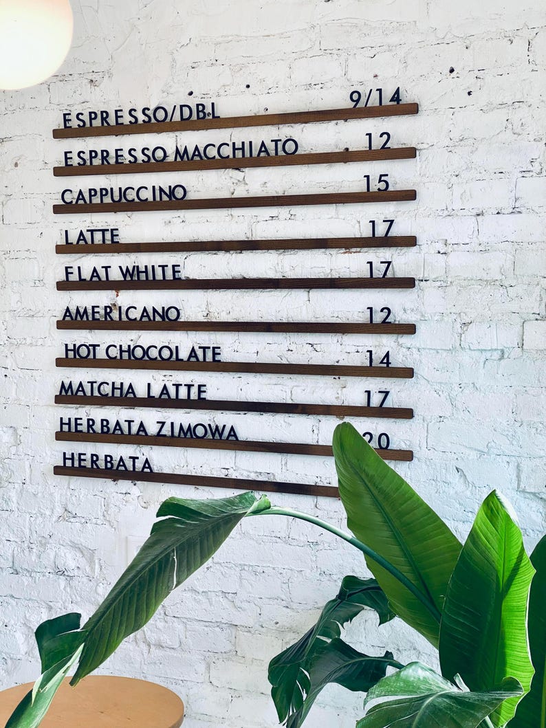 Wooden wall-mounted menu rails displaying coffee options in a café setting