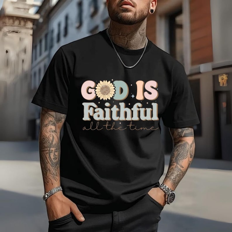 May include: Black t-shirt with the text "GOD IS Faithful all the time" in a colorful, retro font. The word "GOD" features a sunflower design. The shirt is short-sleeved and has a crew neck.