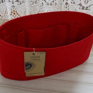 May include: A bright red felt bag organizer with multiple interior pockets. The organizer has a tag that reads "DIVIDE CONQUER". The bag is designed to help organize the contents of a larger bag or tote.