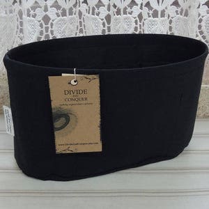 May include: Black fabric organizer with a brown tag that says "Divide and Conquer" and a website address. The organizer is designed to fit inside a handbag.