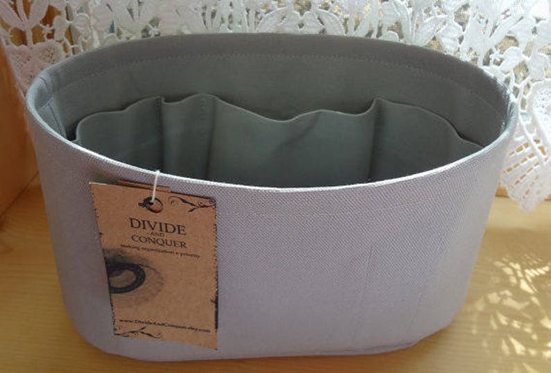 May include: A set of three ceramic mugs with a speckled, matte finish. The mugs are in shades of gray, white, and black. Each mug has a simple, modern design and a rounded handle. The mugs are stacked on top of each other.