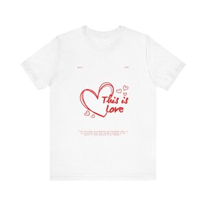 May include: White t-shirt with a red heart and the text "This is Love" in red. The quote "True love knows no boundaries and transcends time; it is an eternal flame that flickers brightly in the hearts of those destined to be together." is printed below the heart.