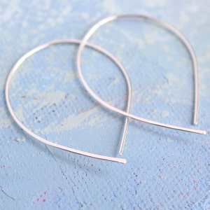 May include: A pair of silver hoop earrings with a thin, delicate wire design. The earrings are simple and elegant, and would be a great addition to any jewelry collection.
