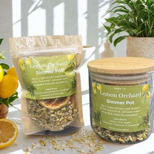 May include: Two containers of "Lemon Orchard Simmer Pot" with a green label. One is a clear bag, the other a glass jar with a wooden lid. The labels include instructions and ingredients: Lemon, Eucalyptus, Rosemary, Cardamom, Cinnamon, and Chamomile.