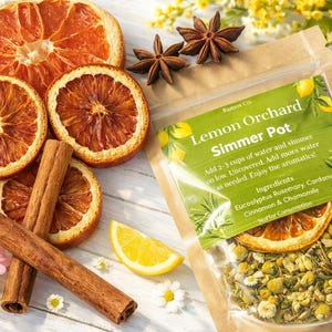 May include: A clear pouch labeled Lemon Orchard Simmer Pot containing dried chamomile, eucalyptus, rosemary, cardamom, and cinnamon. The pouch is surrounded by dried orange slices, cinnamon sticks, star anise, and fresh chamomile flowers.