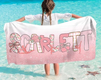Könnte beinhalten: Ein weißes Strandtuch mit dem Namen "SCARLETT" in Rosa. Die Buchstaben sind mit Blumen- und Karomustern, Balletttänzerinnen-Silhouetten und Schleifen verziert. Das Tuch hat einen rosa Glitzerboden.