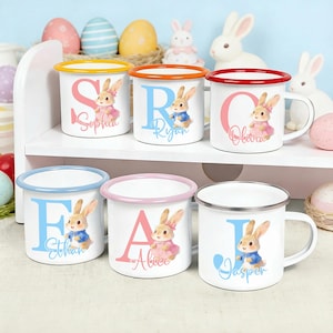 May include: White enamel mugs with colorful rims and handles, each featuring a letter, a bunny illustration, and a name. The mugs have yellow, orange, red, blue, and pink rims. The names include Sophia, Ryan, Olivia, Ethan, Alice, and Jasper.