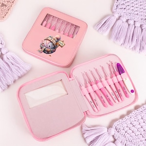 Puede incluir: Un juego de ganchillos rosas en un estuche a juego. El estuche tiene una ventana transparente y un dibujo animado. El juego incluye varios ganchillos de varios tamaños, perfectos para proyectos de manualidades. Los ganchillos son rosas y tienen marcas de tamaño.