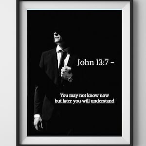 May include: Black and white framed print featuring a person in a suit. The text "John 13:7 - You may not know now but later you will understand" is displayed in white. The print is hanging on a white wall.