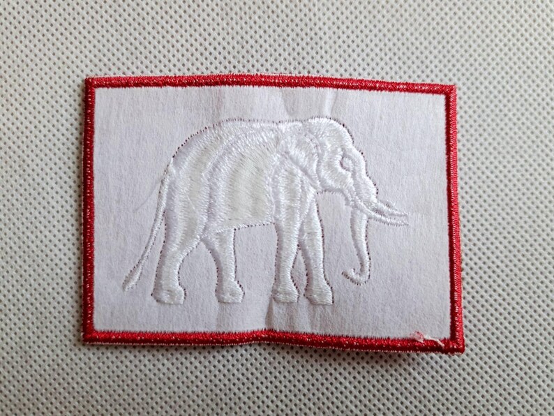 May include: White embroidered patch with a red border, featuring a white elephant silhouette.