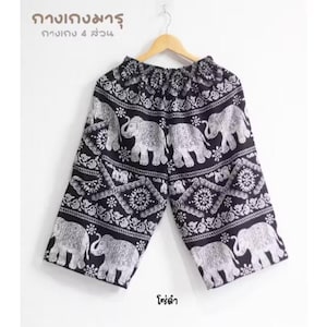 Puede incluir: Pantalones capri estampados en blanco y negro con un motivo de elefante. Los pantalones están colgados de una percha de madera sobre un fondo blanco. El texto de la imagen está en un idioma extranjero.