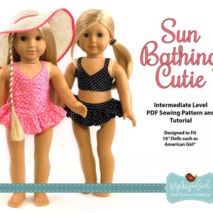 May include: Two dolls wearing swimwear. One doll is in a pink polka dot swimsuit and a straw sun hat with a red trim. The other doll is in a black polka dot bikini. Text on the image reads "Sun Bathing Cutie".