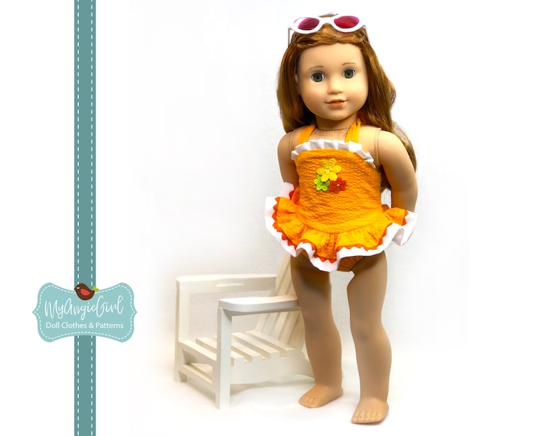 Puede incluir: Una mu&ntilde;eca con un traje de ba&ntilde;o naranja con ribete de volantes blancos y un adorno floral. La mu&ntilde;eca tiene el pelo largo y rojo y lleva gafas de sol blancas. Detr&aacute;s de la mu&ntilde;eca hay una silla de madera blanca. El texto "MyAngieGirl Doll Clothes & Patterns" est&aacute; a la izquierda.