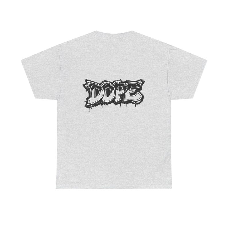 May include: Light grey t-shirt with a black and white graffiti-style design that reads "DOPE". The word is stylized with dripping paint effects, adding a street art aesthetic to the casual wear.