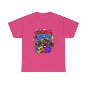 Może przedstawiać: R&oacute;żowa koszulka z kolorową grafiką monster trucka i napisem "Monster Trucks are my Jam". Projekt wykorzystuje żywe kolory zieleni, błękitu, fioletu i ż&oacute;łci, tworząc zabawny i energiczny wygląd.